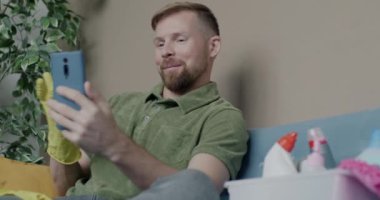 Kauçuk eldivenli profesyonel temizlikçi internette temizlik ürünlerini tartışıyor. Modern teknoloji ve iletişim konsepti.