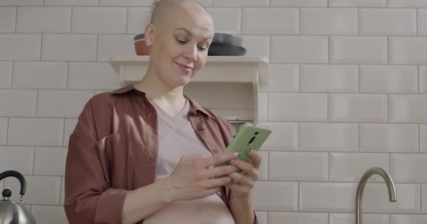 家のキッチンでオンラインチャットを使用してかわいい妊娠中の女性のゆっくりとした動きの肖像画 ソーシャルメディアと妊娠のコンセプト — ストック動画