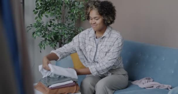漂亮的非洲裔美国家庭主妇在家里洗衣服 整理衣服 折叠衣服 然后把衣服堆在衣橱里 家务劳动和人的概念 — 图库视频影像