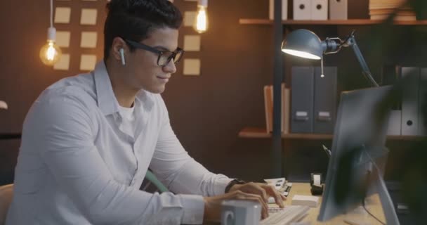 在晚上的黑暗的办公室里 用电脑对着镜头微笑的阿拉伯男人慢动作的肖像 现代技术和商人概念 — 图库视频影像