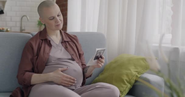 自宅で健康な妊娠を楽しんでいる赤ちゃんの超音波画像を見ている未来の母親のゆっくりとした動きの肖像画 家族計画と母性のコンセプト — ストック動画