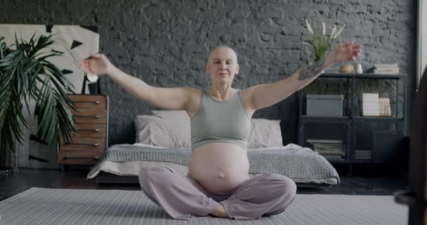 自宅のベッドルームでリラックスした場所に座って瞑想している美しい妊婦のゆっくりとした動きの肖像画 瞑想と妊娠のコンセプト — ストック動画