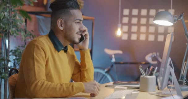 Blízkovýchodní Muž Mluví Mobilním Telefonu Večer Dívá Obrazovku Počítače Probírá — Stock video