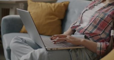 Karanlık bir dairede sosyal medyanın keyfini çıkarırken dizüstü bilgisayar kullanan kaygısız genç bir kadının portresi. İnsanlar ve modern teknoloji kavramı.