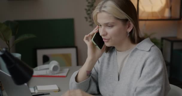 Mujer Joven Hablando Por Teléfono Móvil Trabajando Con Ordenador Portátil — Vídeo de stock