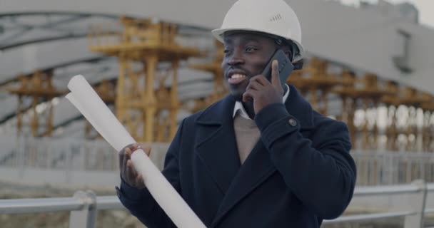 Afroamerykański Architekt Omawiający Projekt Telefonie Komórkowym Trzymający Plany Planów Stojących — Wideo stockowe