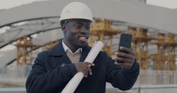 Афроамериканский Инженер Строитель Делает Онлайн Видео Звонок Используя Смартфон Обсуждая — стоковое видео