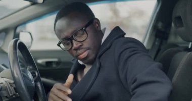 Şehir caddesinde modern bir arabada oturan Afrikalı Amerikalı adam emniyet kemerini takıyor. Ulaşım ve trafik güvenliği kavramı.