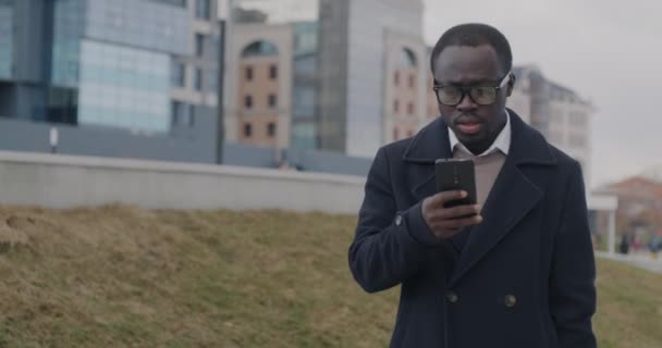 非洲裔美国企业家在市区行走并使用智能手机应用程序的慢动作肖像 在线通信和商人概念 — 图库视频影像