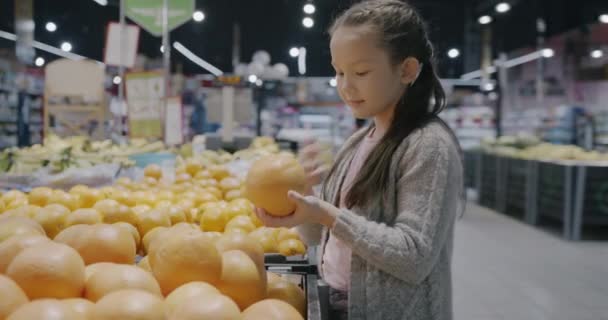 Sevimli Küçük Kız Modern Süpermarkette Taze Narenciye Alışverişini Tek Başına — Stok video