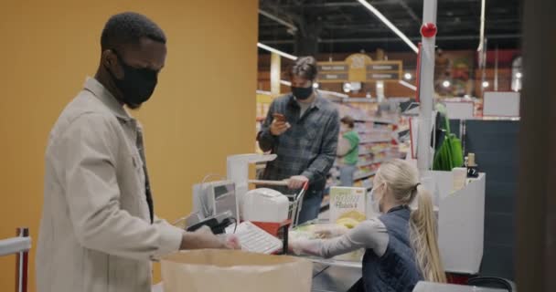 Афроамериканец Маске Покупает Еду Супермаркете Кассе Время Кассир Продает Продукты — стоковое видео