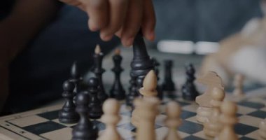 Çocuk ve yetişkinin yakın çekimde satranç taşları içeride oyuna yoğunlaşır. Entellektüel rekabet ve spor kavramı.