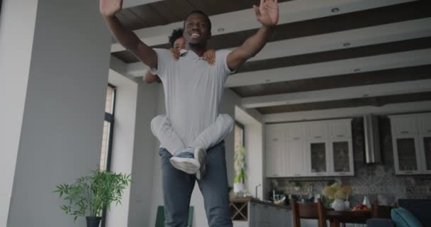 强壮的非裔美国人父亲做运动 背着小男孩在家里享受活动 父亲和运动员概念 — 图库视频影像