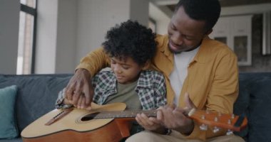 Sevimli bir çocuğa gitar çalmayı öğretirken çocuk evde müzik aleti öğreniyor. Tecrübe ve becerileri çocukla paylaşan adam.