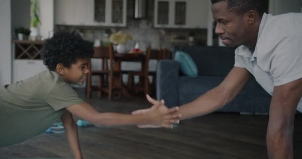 快乐的非裔美国家庭父亲和儿子一起做俯卧撑训练 并在家里做高五手势 人与积极的生活方式概念 — 图库视频影像