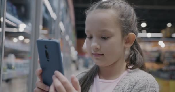 Glada Barn Med Hjälp Smartphone Ansökan Vidröra Skärmen Stående Snabbköpsavdelningen — Stockvideo
