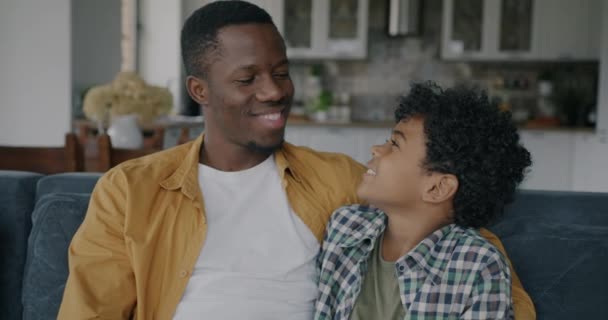 快乐的非裔美国男人和小男孩在公寓里一边聊天一边看着相机和微笑 家庭关系和幸福概念 — 图库视频影像