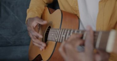 Erkek eli gitar çalarken Afrikalı Amerikalı adam içeride yaratıcı aktivitelerden zevk alıyor. Müzik aleti ve insanların konsepti.