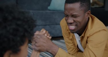 Neşeli Afrikalı Amerikalı adam bilek güreşi yarışmasında çocuk kazanıyor ve evdeki küçük oğluna sevgisini ifade ediyor. Spor ve mutlu aile kavramı.