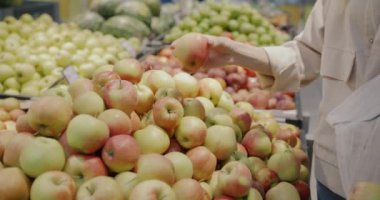 Kadın elinin taze organik elma seçerken yakın plan çekimi süpermarkette birden fazla kullanılmış poşet alışverişi yapıyor. Sağlıklı gıda ve tüketim kavramı.