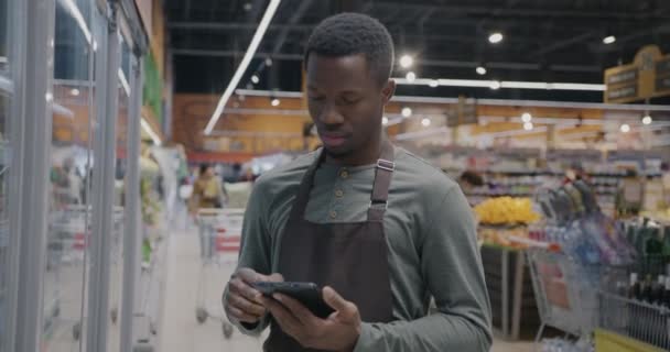 スーパーマーケットで在庫と品質管理を行うタブレットを使用したアフリカ系アメリカ人の肖像画 現代のガジェットと小売ビジネスコンセプト — ストック動画