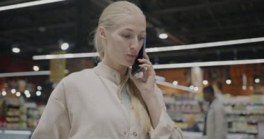 Mutlu genç bayan süpermarkette cep telefonu alışverişi yapmayı tartışıyor. Cep telefonu iletişimi ve kablosuz aygıt kavramı.
