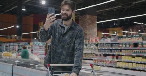 Wesoły Facet Zakupy Supermarkecie Podejmowania Rozmowy Wideo Online Dyskusji Żywności — Wideo stockowe