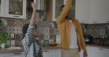 Yetişkin bir adam ve küçük bir çocuk mutfakta dans ediyor baba oğul ilişkisinin tadını çıkarıyorlar. Aile ve eğlence etkinliği konsepti.
