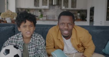 Çok mutlu bir aile babası ve çocuğunun portresi TV 'de futbol seyrediyor ve oyundan zevk alıyor. Spor hayranları ve aile yaşam tarzı konsepti.