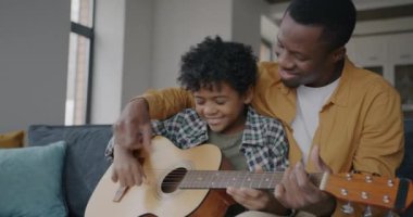 Neşeli insanlar baba ve oğul gitar çalıp evde eğleniyorlar. Müzik aleti ve mutlu çocukluk konsepti.