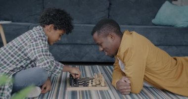 Babamın, evde çocuklara entellektüel oyunlar öğreten Afrikalı Amerikalı bir çocukla satranç oynaması. Çocukluk ve babalık kavramı.