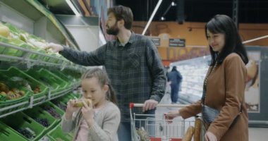 Mutlu bir aile babası ve kızının marketten meyve seçerken yavaş hareket etmesi. Alışveriş ve perakende satış konsepti.