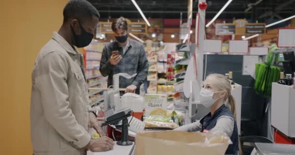 アフリカ系アメリカ人男性が スーパーマーケットのレジ係から食料を購入し スマートウォッチで支払う モダンテクノロジーと小売事業コンセプト — ストック動画