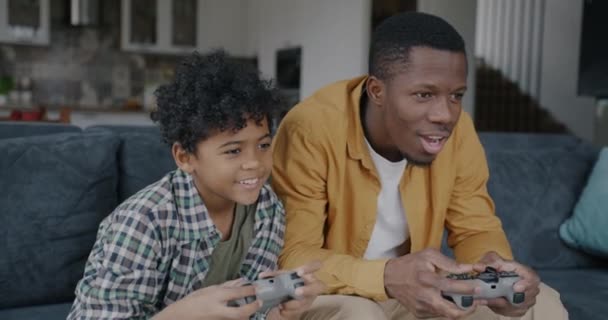 爸爸和儿子在家里玩电子游戏 手握操纵杆 一起做击掌放松 家庭生活方式和现代技术概念 — 图库视频影像