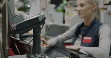 Neşeli kasiyer kasada çalışırken müşteriler süpermarkette akıllı telefonla ödeme yapıyor. Alışveriş ve modern teknoloji konsepti.