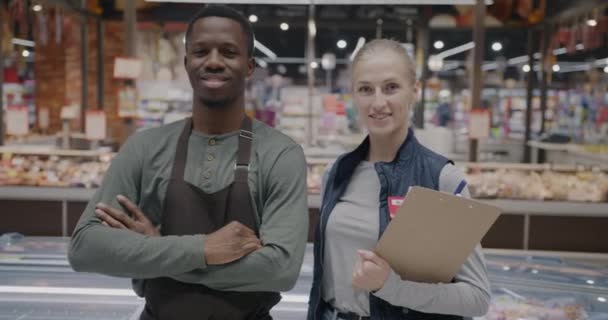 男人和女人的慢动作肖像超级市场的工作人员站在商店里笑着看着相机 人与零售企业概念 — 图库视频影像