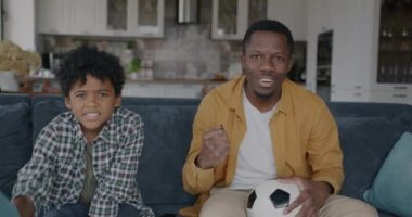 Baba ve oğul portresi, televizyonda futbol seyreden Afro-amerikalıları heyecanlandırdı. Spor ve aile yaşam tarzı konsepti.