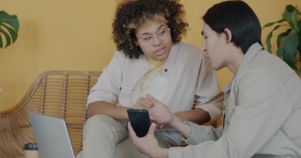 Веселые Студенты Афроамериканка Азиат Используют Смартфон Вместе Разговаривая Колледже Современное — стоковое видео
