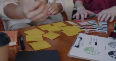 Bir grup girişimci masa başında projeyle meşgulken, ellerinizi yapışkan notlarla yakın plan yapın. İş ve yaratıcı tasarım konsepti.