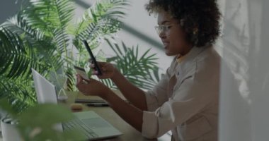 Evde plastik kartla akıllı telefonlardan sipariş veren Afrikalı Amerikalı serbest çalışan bir kadın. İş ve finans kavramı.