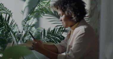 Akıllı telefon kullanan Afro-Amerikalı kız öğrenci dairede internet içeriğinin keyfini çıkarıyor. İnternet iletişimi ve milenyum kavramı.