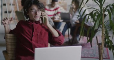 Cep telefonuyla konuşan ve kreaitve kafede çalışan dizüstü bilgisayar kullanan serbest çalışan erkek profesyonel iletişim üzerine yoğunlaşmış. Serbest meslek ve cep telefonu bağlantısı.