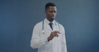 Afrika kökenli Amerikalı bir adamın elinde şırıngayla gri arka planda iğne hazırlarken yavaş çekimde çekilmiş bir portresi. Sağlık ve Tıp Konsepti.
