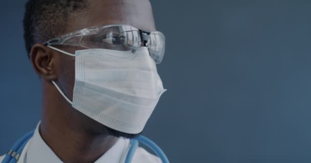 Zbliżenie Powolny Portret Afroamerykańskiego Lekarza Masce Okularach Obracających Się Kamery — Wideo stockowe