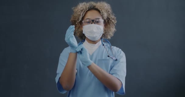 Afrikalı Amerikalı Kadın Doktorun Gri Arka Planda Duran Lastik Eldivenlerini — Stok video