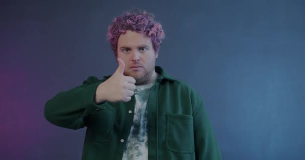 在紫色背景下 将不高兴的年轻人的大拇指改为大拇指向下的手势的肖像 负面情绪和人的概念 — 图库视频影像