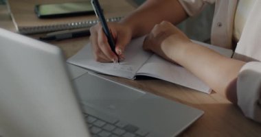 Kadın el yazısını not defterine yakın çekim ve öğrenci evinde çalışırken dizüstü bilgisayar kullanma. Çevrimiçi eğitim ve bilgi kavramı.