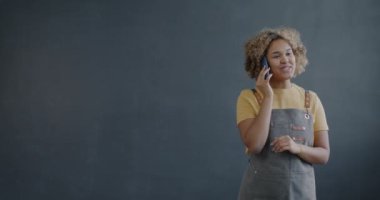 Afrika kökenli Amerikalı girişimci Afrika kökenli Amerikalı bir kadının portresi cep telefonuyla fotokopi uzayının gri arka planında konuşuyor. Hücre iletişimi ve küçük işletme kavramı.