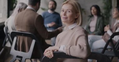 Rehabilitasyon merkezinde grup terapisi sırasında mutlu hissederek kameraya bakan olgun kadının portresi. İnsanlar ve psikoloji kavramı.