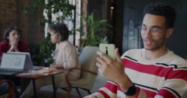 Afrikalı Amerikalı girişimci, akıllı telefon konuşmalarıyla çevrimiçi video kalorifer yapıyor. İş yerinde iş konuşuyorlar. Gadget ve iletişim konsepti.